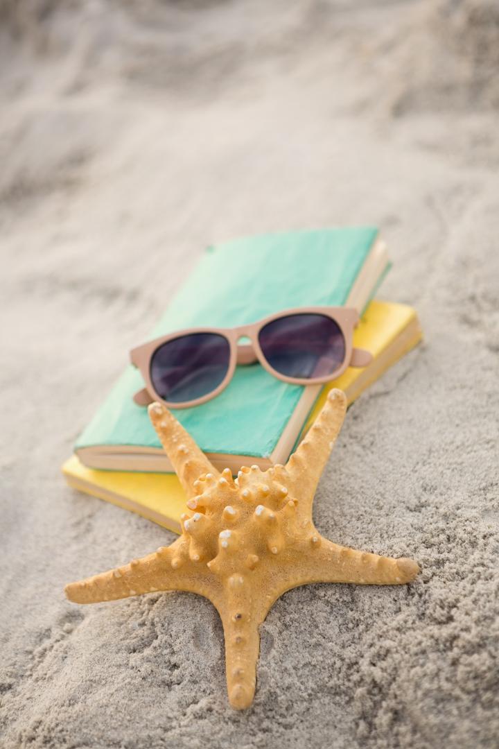 Starfish, sunglasses and books on sand  - Free Images, Stock Photos and Pictures on Pikwizard.com