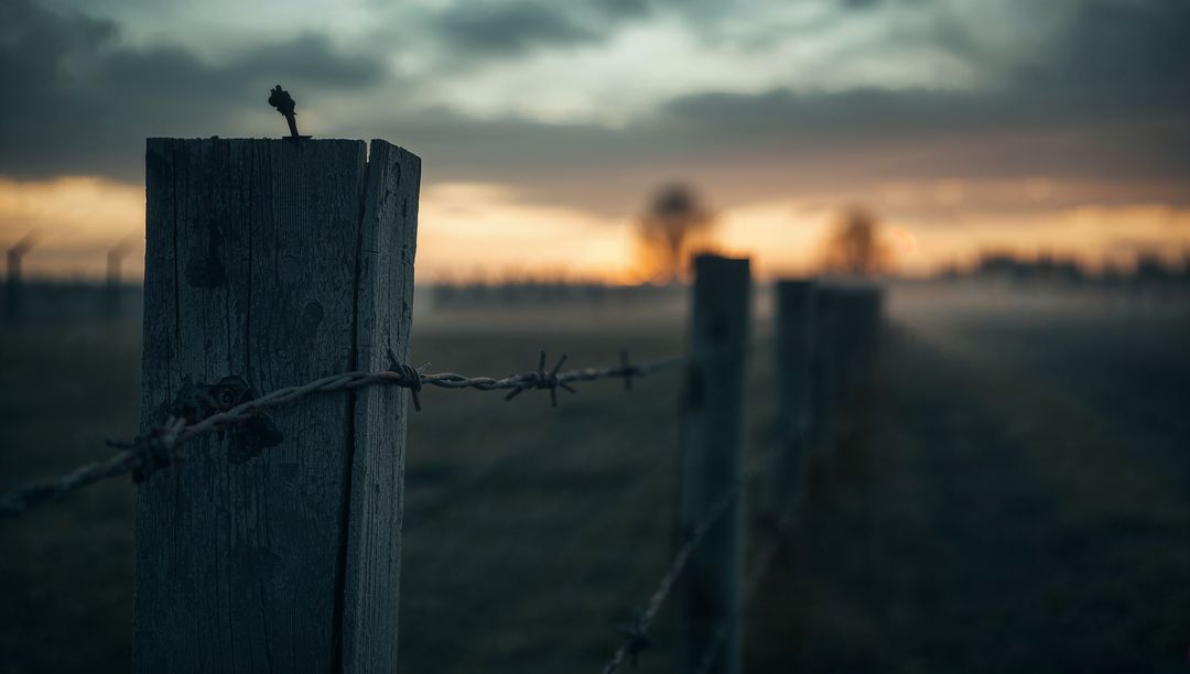 Weathered Fence Post with Barbed Wire at Dusk