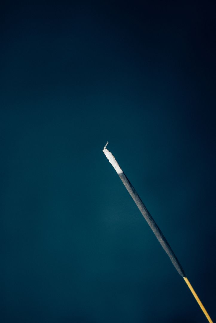 Lit Incense Stick Burning Against Dark Blue Background - Free Images, Stock Photos and Pictures on Pikwizard.com