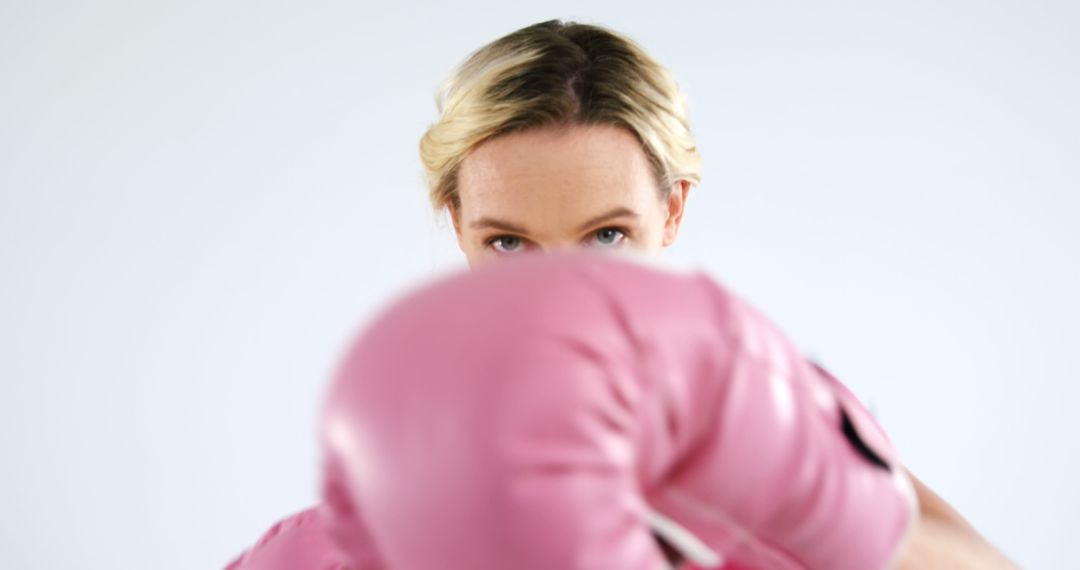 Determined Woman Wearing Pink Boxing Gloves Throwing Punch - Free Images, Stock Photos and Pictures on Pikwizard.com