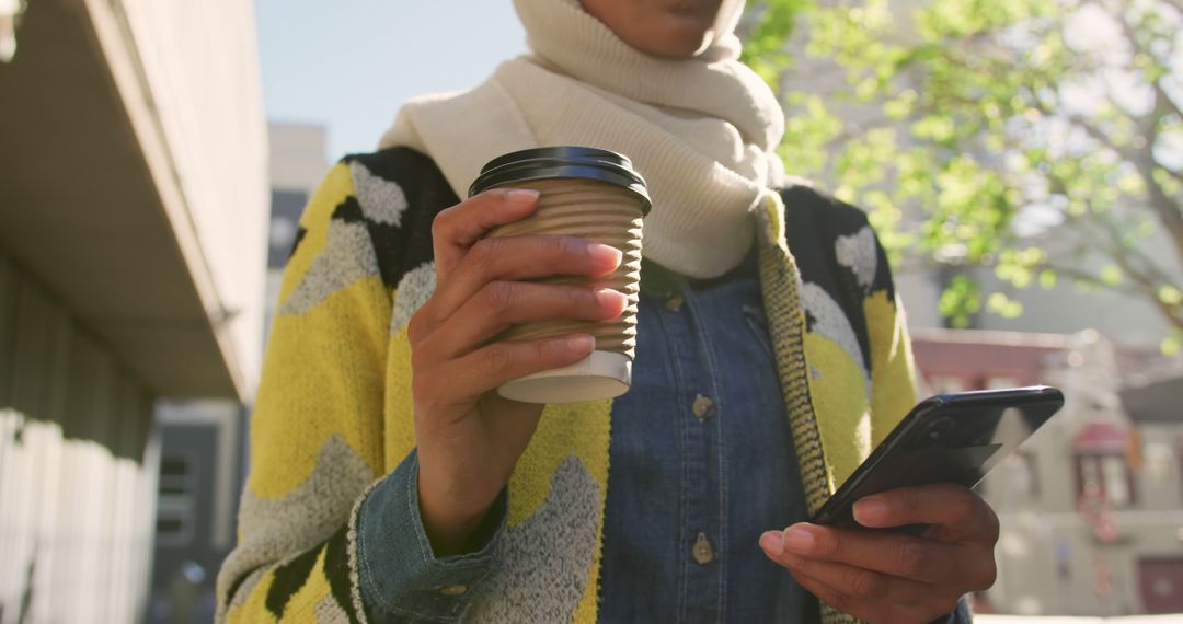 Woman in hijab holding coffee cup and using smartphone outdoors - Free Images, Stock Photos and Pictures on Pikwizard.com