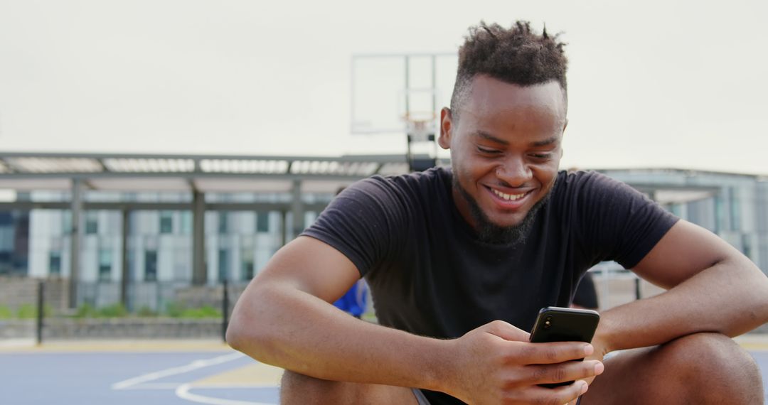 Joyful Basketball Player Using Smartphone on Court Break