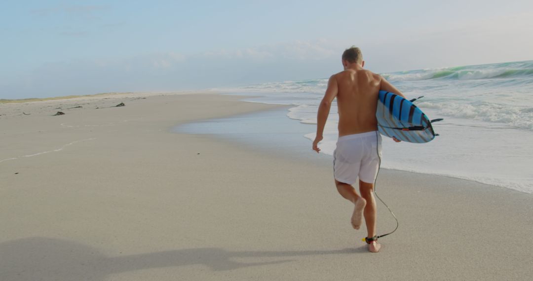 Surfer Running Toward Ocean with Surfboard
