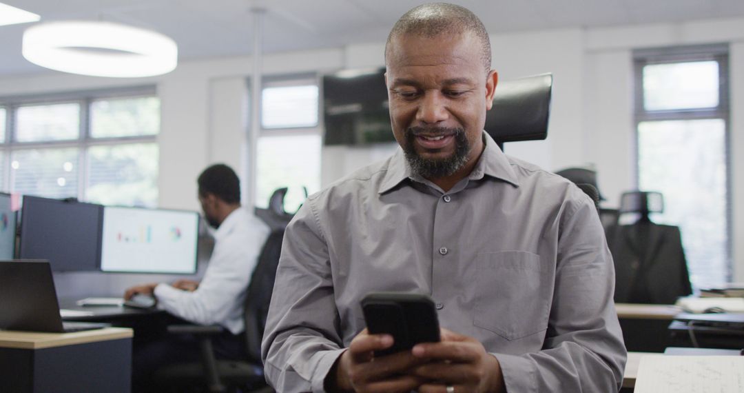 Businessman Smiling While Using Smartphone in Office - Free Images, Stock Photos and Pictures on Pikwizard.com