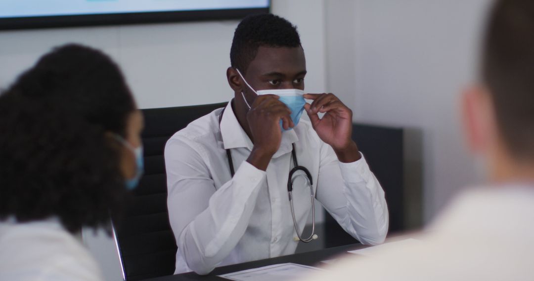 Young African Doctor Adjusting Face Mask in Medical Meeting - Free Images, Stock Photos and Pictures on Pikwizard.com