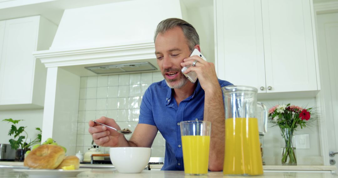 Man Having Breakfast and Talking on Phone in Modern Kitchen - Free Images, Stock Photos and Pictures on Pikwizard.com