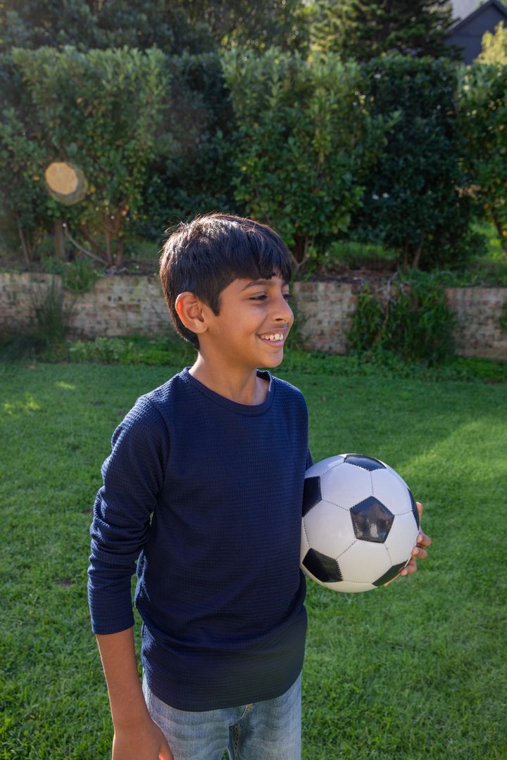 Smiling Boy in Garden with Soccer Ball Embracing Outdoor Play