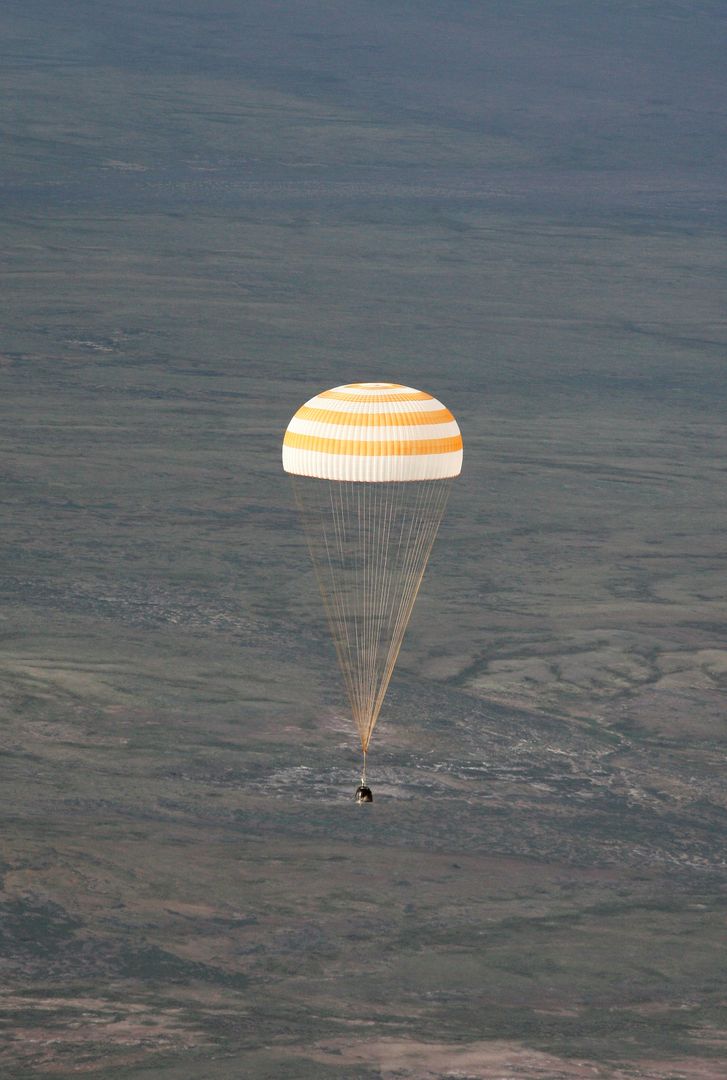 Soyuz TMA-9 spacecraft descending with parachute over Kazakhstan landscape - Free Images, Stock Photos and Pictures on Pikwizard.com