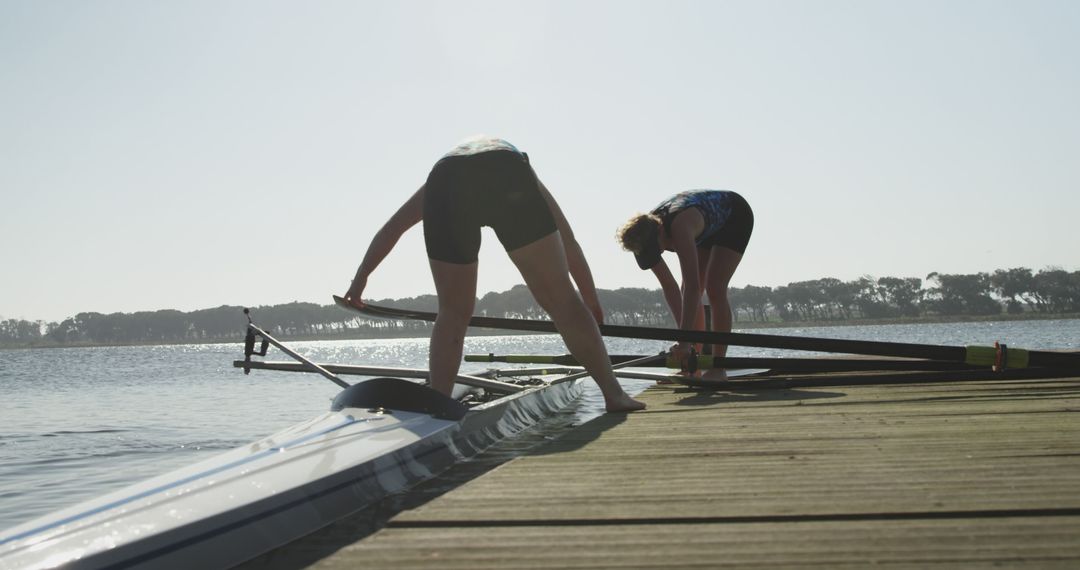 Female Rowers Preparing Boat by Lake on Sunny Day - Free Images, Stock Photos and Pictures on Pikwizard.com