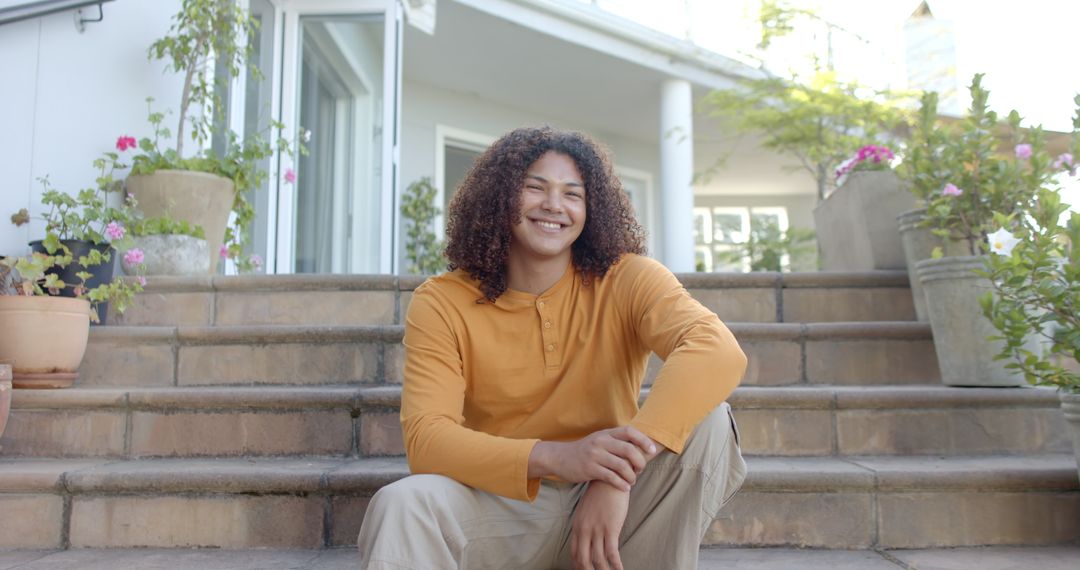 Young Man Smiling While Sitting on Outdoor Steps - Free Images, Stock Photos and Pictures on Pikwizard.com