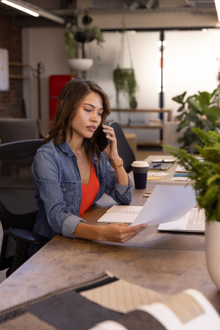 Businesswoman Multitasking with Smartphone and Documents in Modern Office