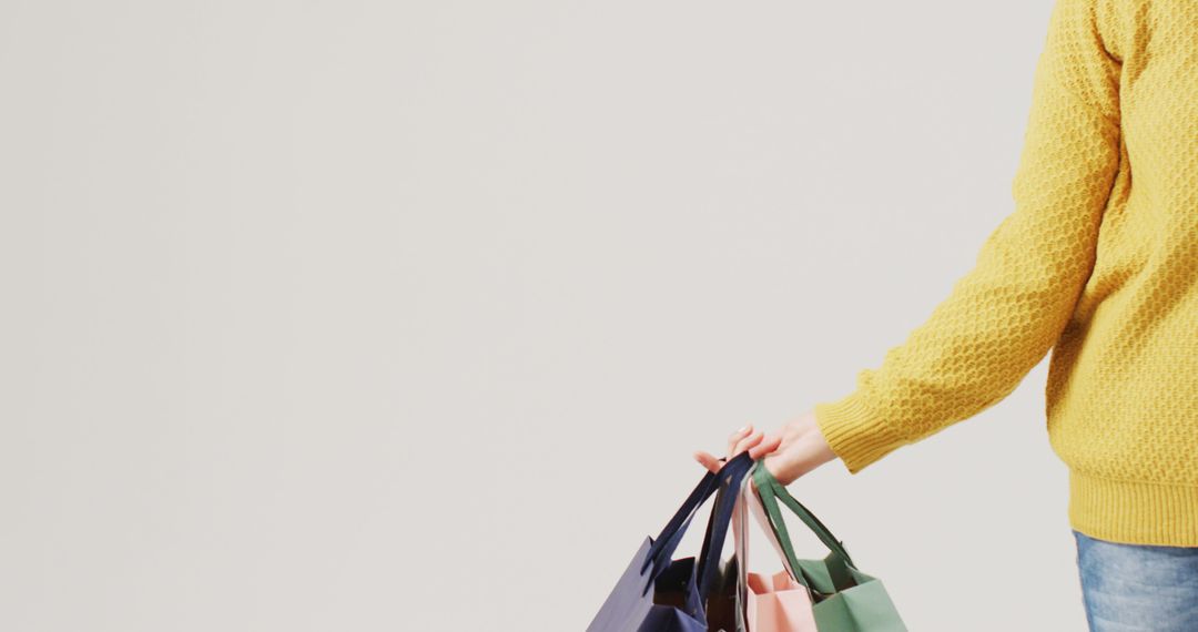 Person Holding Shopping Bags Against a Plain Background - Free Images, Stock Photos and Pictures on Pikwizard.com