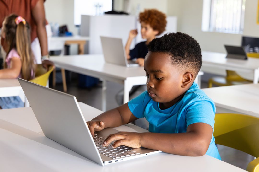 African American Boy Using Laptop in Bright Classroom Learning Tech Skills and Coding