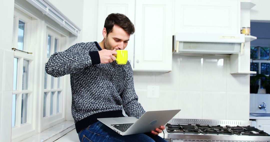 Young Man Drinking Coffee While Working from Home in Kitchen - Free Images, Stock Photos and Pictures on Pikwizard.com