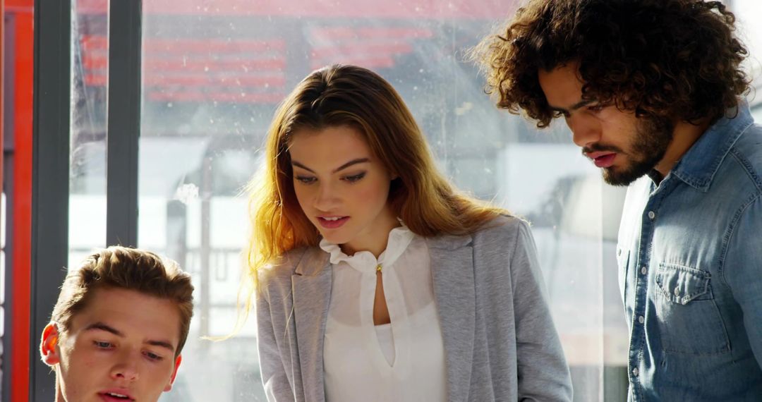 Young team collaborating by sunlit office window, brainstorming and planning ideas