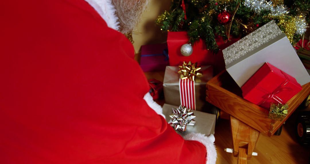 Santa Claus Placing Decorated Christmas Presents Under Tree - Free Images, Stock Photos and Pictures on Pikwizard.com