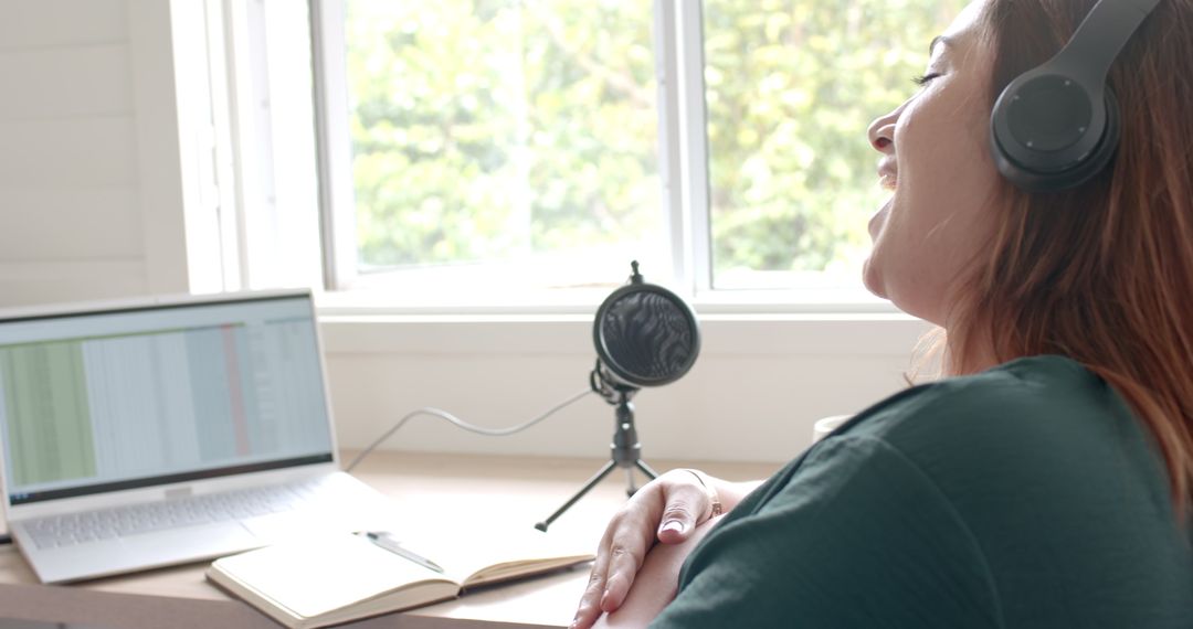 Joyful Woman Podcasting With Laptop and Microphone at Home