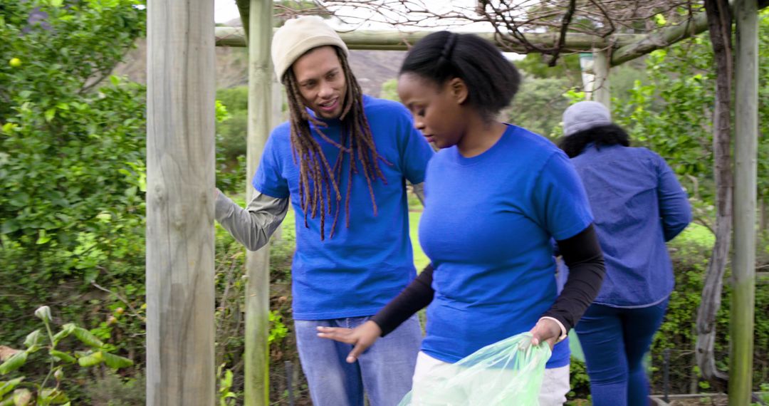 Community Volunteers Collecting Garden Debris Under Pergola During Neighborhood Green Space Cleanup
