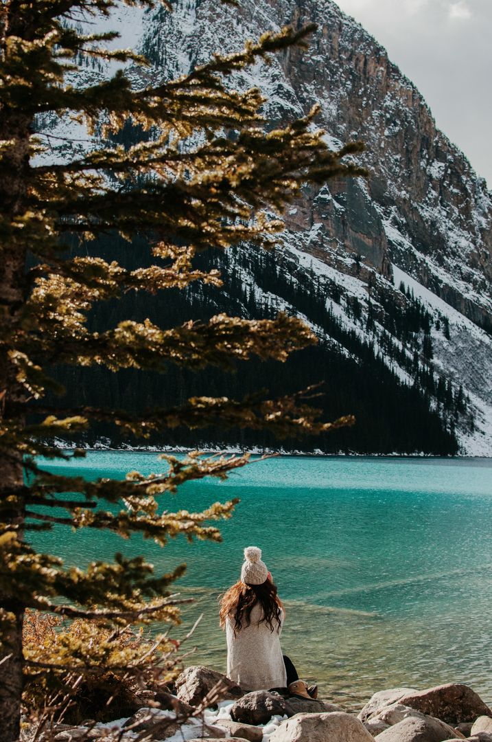 Woman Sitting by Lake with Snow-Covered Mountain Background - Free Images, Stock Photos and Pictures on Pikwizard.com