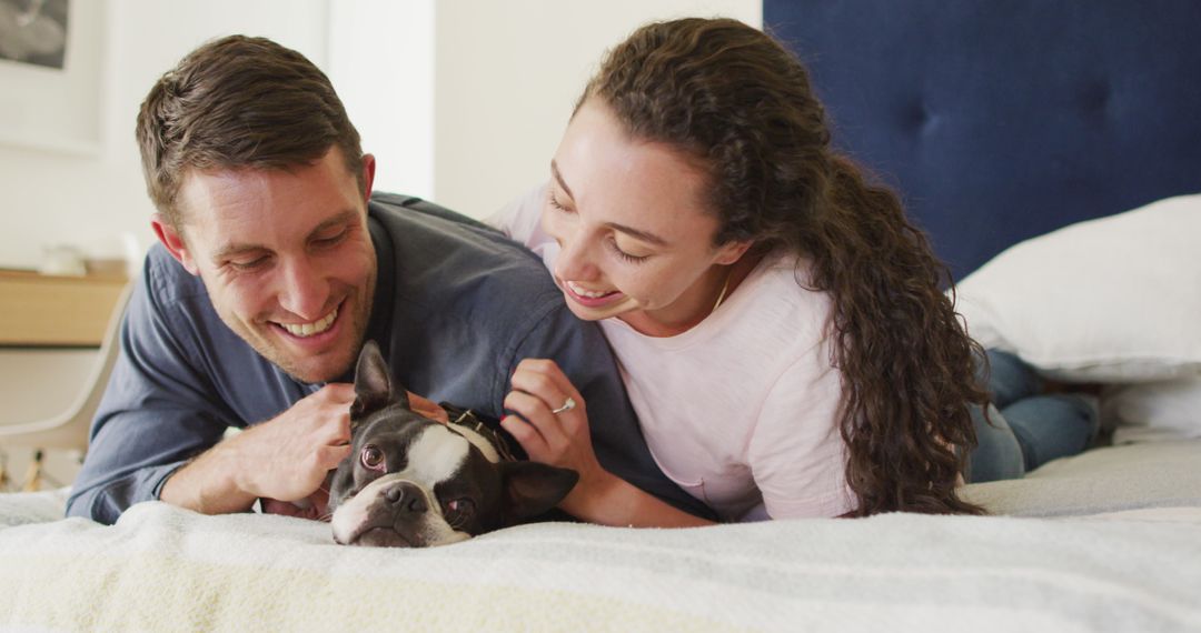 Joyful Couple Relaxing with Dog on Bedroom Bed at Home