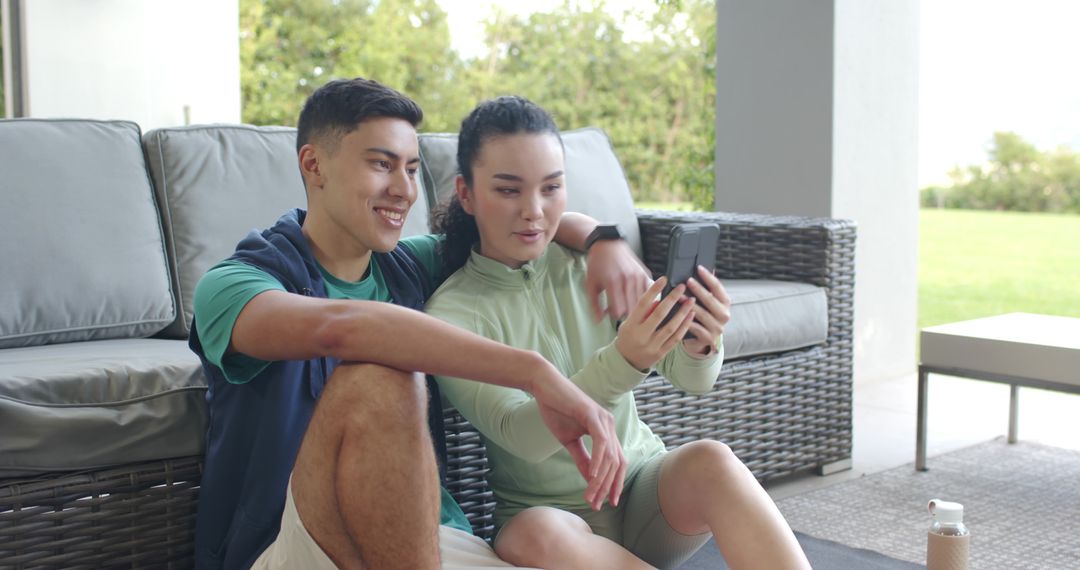 Asian Couple Relaxing on Patio Using Smartphone