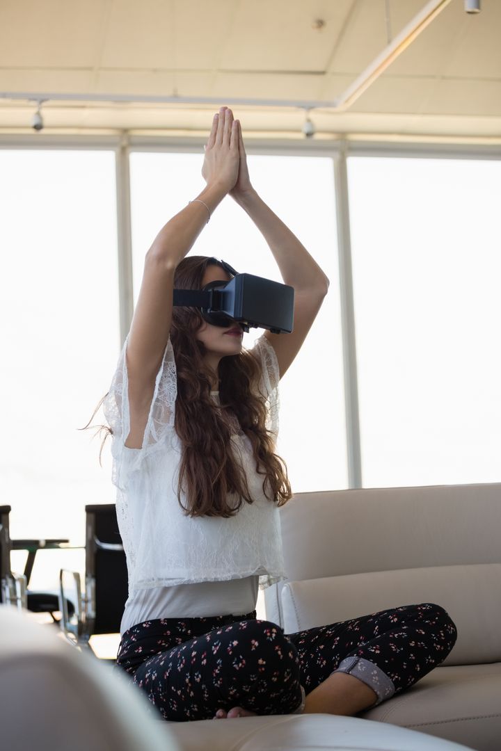 Young businesswoman doing yoga while using virtual reality on sofa  - Free Images, Stock Photos and Pictures on Pikwizard.com