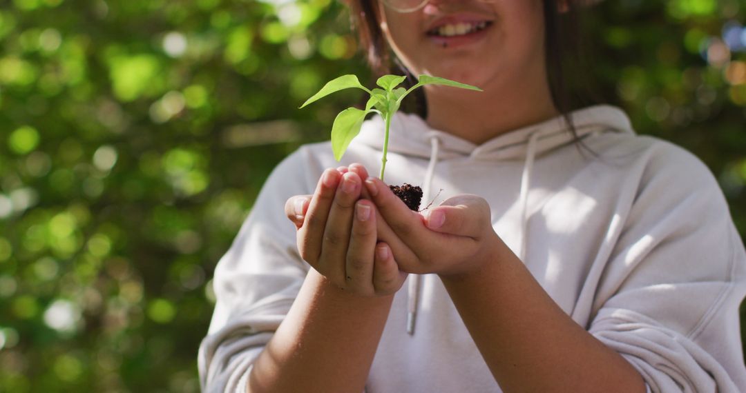 Young girl holding small seedling in outdoor garden - Free Images, Stock Photos and Pictures on Pikwizard.com