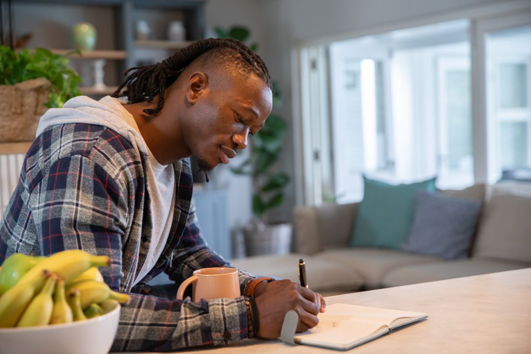 Concentrated Young Adult Writing at Home Kitchen Counter