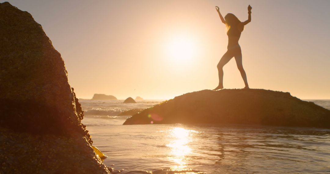 Silhouette of Woman Dancing on Rock by Ocean at Sunset - Free Images, Stock Photos and Pictures on Pikwizard.com