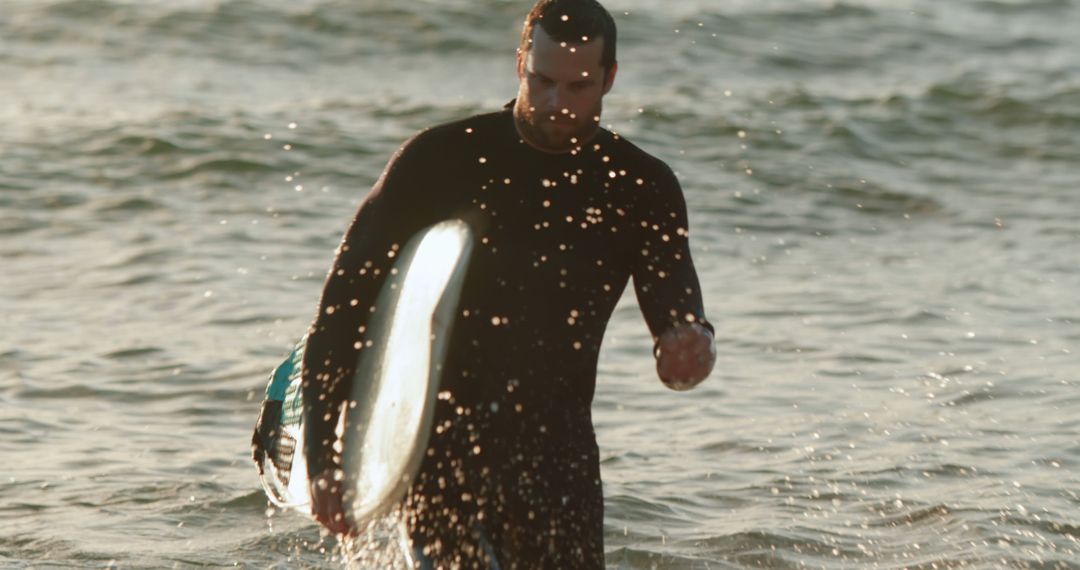 Man Emerging from Ocean with Surfboard at Sunset - Free Images, Stock Photos and Pictures on Pikwizard.com