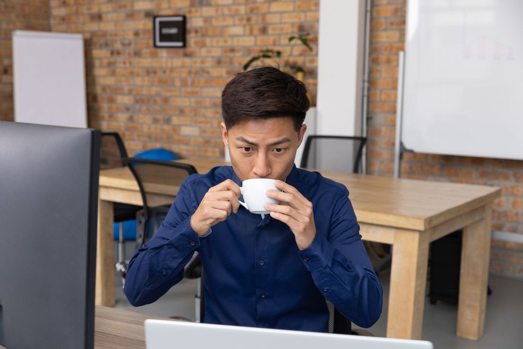 Businessman Drinking Coffee While Working Indoors at Modern Workspace