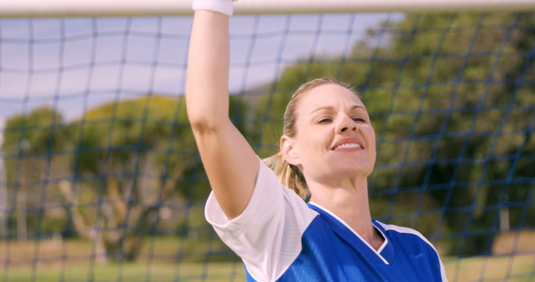 Female soccer player celebrating goal with arm raised wearing blue jersey - Free Images, Stock Photos and Pictures on Pikwizard.com