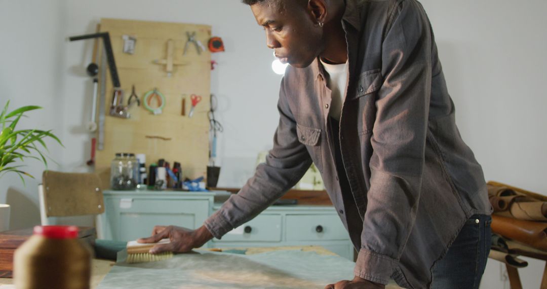 African American Craftsman Brushing Leather in Workshop