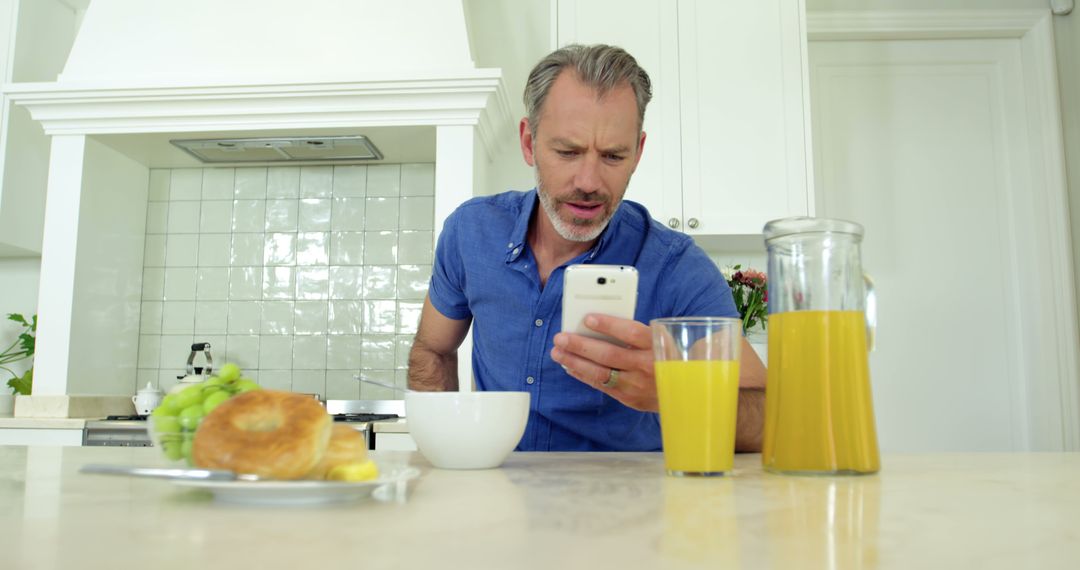 Middle-aged Man Checking Smartphone during Breakfast at Home - Free Images, Stock Photos and Pictures on Pikwizard.com