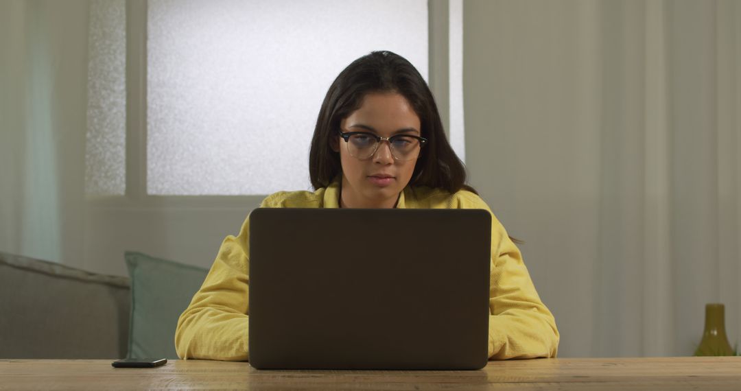 Focused woman working on laptop at home with eyeglasses - Free Images, Stock Photos and Pictures on Pikwizard.com