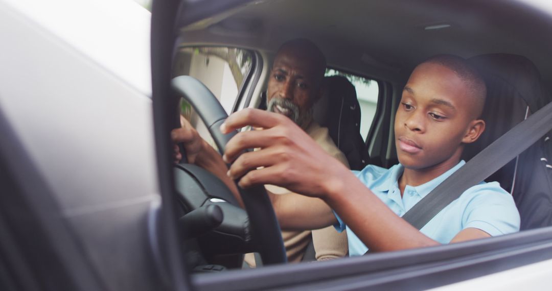 Image of focused african american father learning son how to drive a car - Free Images, Stock Photos and Pictures on Pikwizard.com