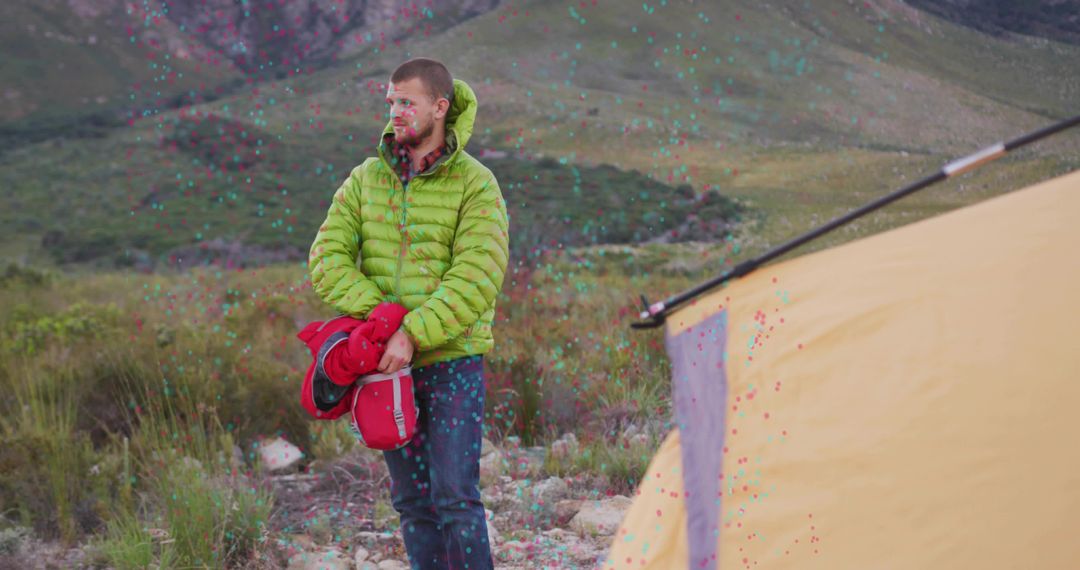 Camper in Green Jacket Holding Red Mat Near Mountain Tent