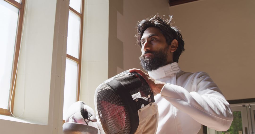 Focused Fencer Preparing for Duel in Gym Sunlight