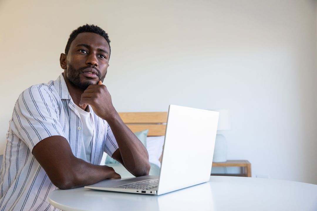 Focused Man Working from Home with Laptop in Minimalist Room
