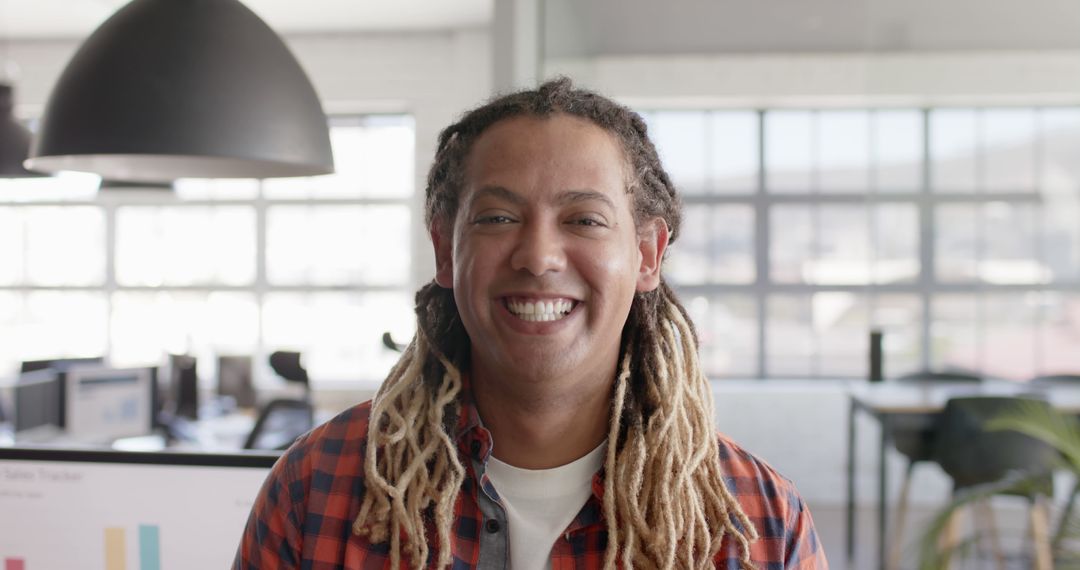 Portrait of happy biracial businessman with dreadlocks looking at camera and smiling at office - Free Images, Stock Photos and Pictures on Pikwizard.com