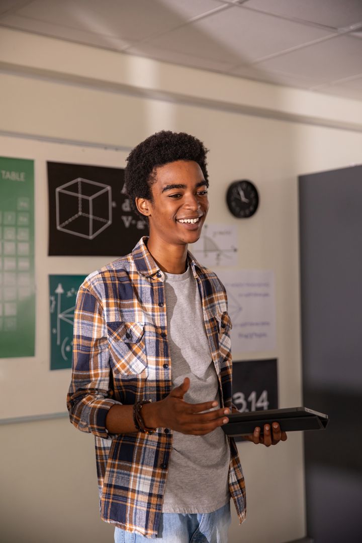 African American student presenting with tablet and gesturing in modern classroom