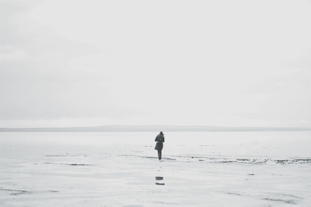 Solitary Figure Walking on Vast Beach in Misty Weather - Free Images, Stock Photos and Pictures on Pikwizard.com