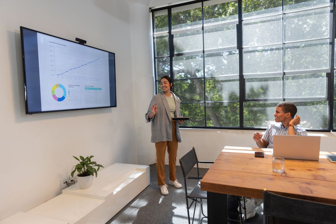 Diverse Team Analyzing Data on Wall-Mounted Screen in Modern Meeting Room