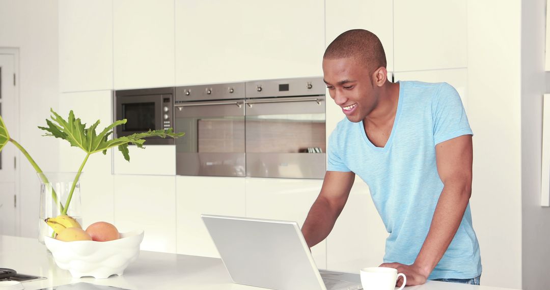 Young African American man working on a laptop in modern kitchen - Free Images, Stock Photos and Pictures on Pikwizard.com