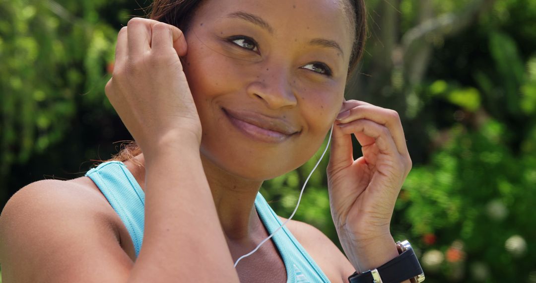 Smiling Woman Outdoors Putting on Earphones during Exercise - Free Images, Stock Photos and Pictures on Pikwizard.com