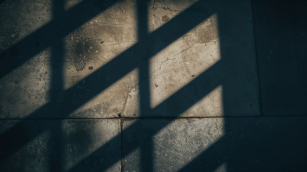 Casting diagonal window shadows across empty concrete floor with cracked grout texture