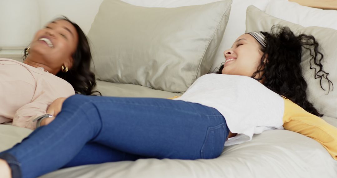 Joyful Friends Relaxing on Bed with Laughter