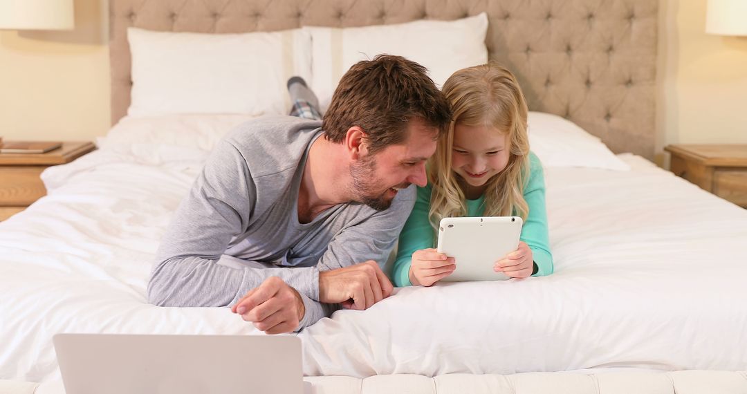 Father and Daughter Lying on Bed Using Digital Tablet Together - Free Images, Stock Photos and Pictures on Pikwizard.com