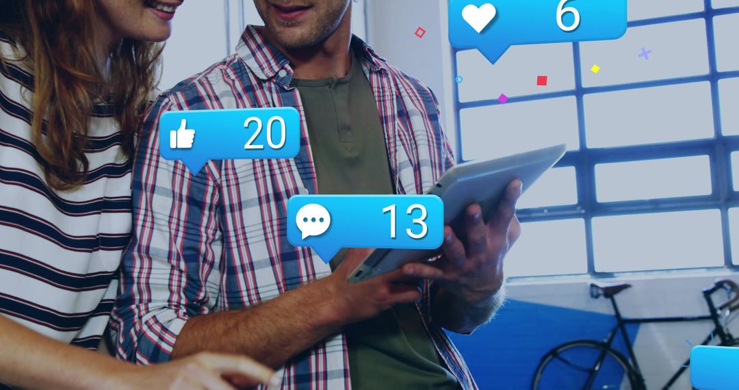 Couple interacting on tablet with floating social media notifications in creative workspace