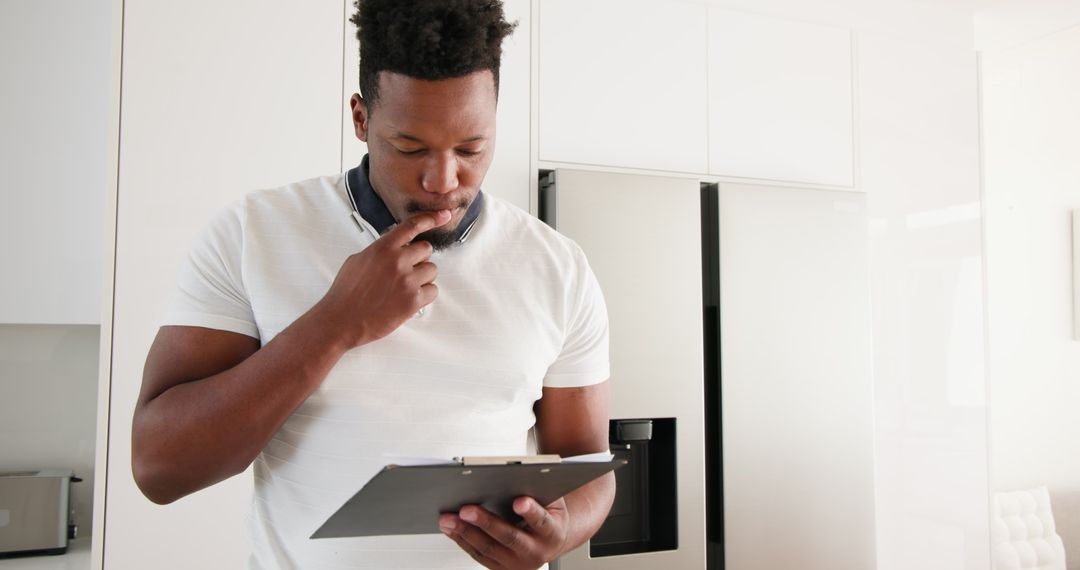 Man Contemplating Checklist Standing in Kitchen